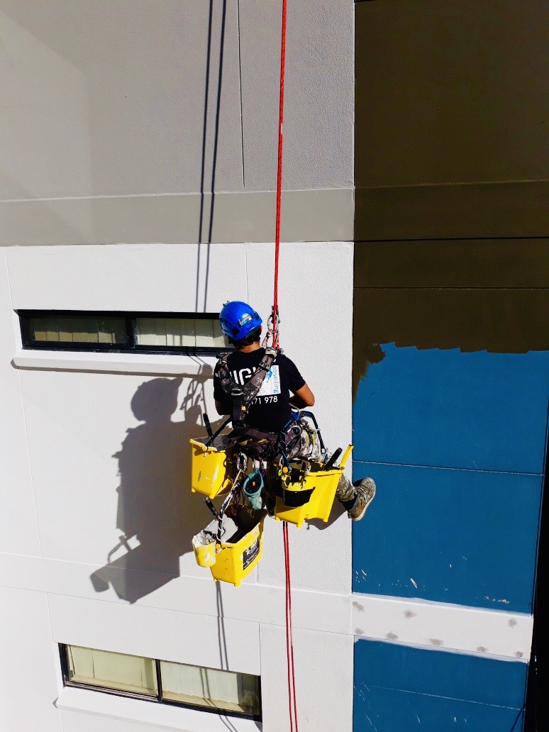 High Solutions Abseiling worker painting a building exterior using rope access